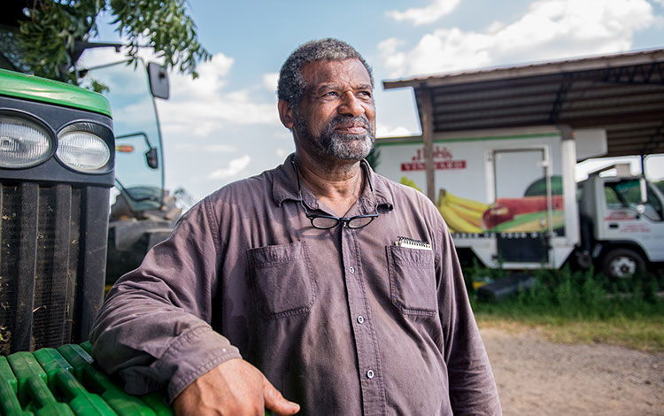 Hombre se para con un tractor, orgulloso de su experiencia agrícola.